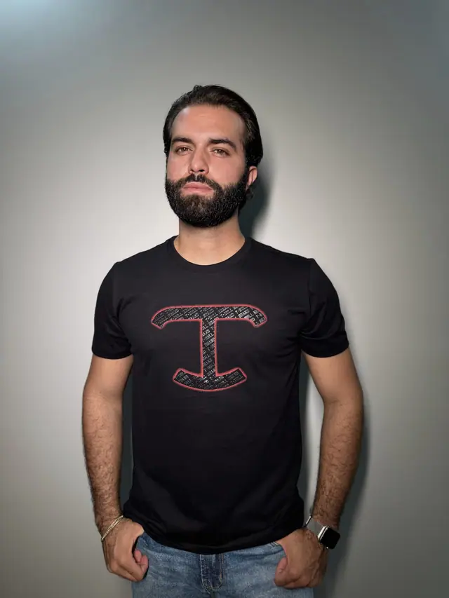 Homem de camiseta preta de malha TBull com o monograma T em vermelho no centro do peito.